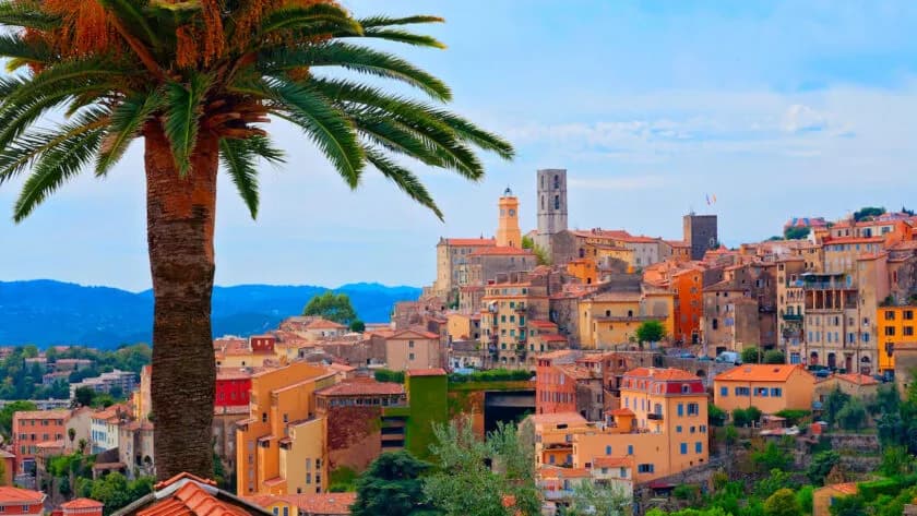 Facciate colorate e campanili di Grasse dietro una palma